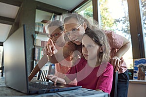 Mother helping for two girls infront of the laptop