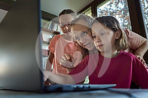 Mother helping for two girls infront of the laptop