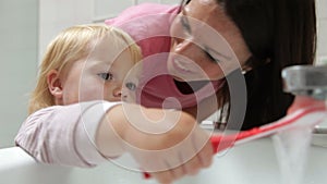 Mother Helping Young Girl To Brush Teeth In Bathroom