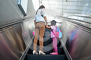 Mother helps alleviate fears on her daughter`s first ride on an escalator.