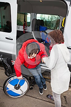 Mother helps her handicapped son off the school bus.