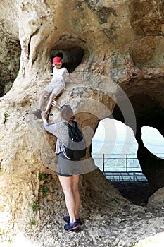 Mother helps her son descend from cliff in grotto on Una-Koz ridge