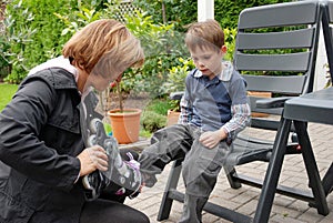 Mother helps her son to put on roller skates