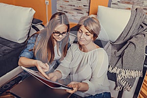 Mother helps her teenage daughter with homework, learning and reading book together