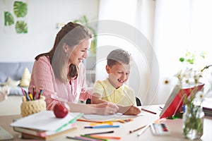 Mother helps son to do lessons. home schooling, home lessons. the tutor is engaged with the child, teaches to write and count. out