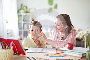 Mother helps son to do lessons. home schooling, home lessons. the woman is engaged with the child, checks the job done. outside