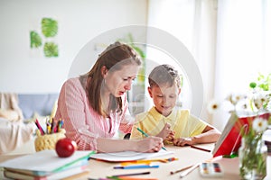 Mother helps son to do lessons. home schooling, home lessons. the tutor is engaged with the child, teaches to write and count photo