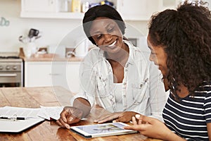 Mother Helps Teenage Daughter With Homework Using Digital Tablet