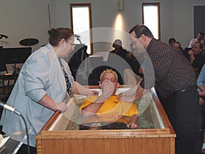 A mother helps to baptize her son