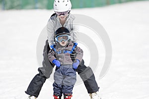 Mother Helps Tpoddler Boy Ski Downhill. Dressed Safely