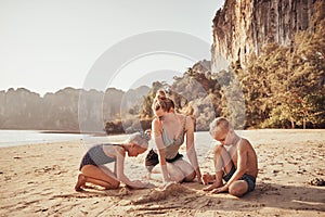 Mother and her adorable children playing on a sandy beach