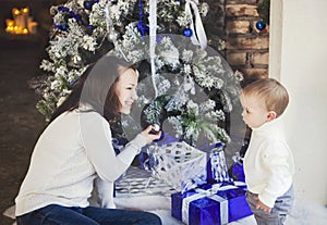 Mother with her baby boy siting near the Christmas tree