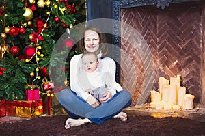 Mother with her baby boy siting near the Christmas tree