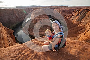 A mother and her baby boy are sitting at the edge of the cliff n