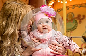 Mother and her baby daughter on merry-go-round