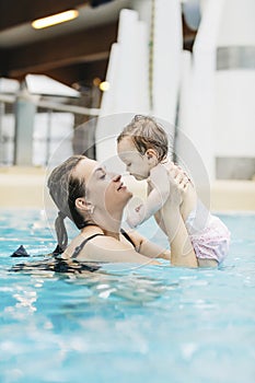 Mother with her baby daughter swim in the pool in waterpark
