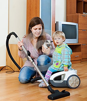Mother with her baby doing house cleaning in the room