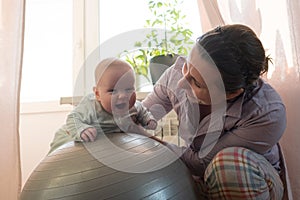 Mother and her baby girl having fun with gymnastic ball.