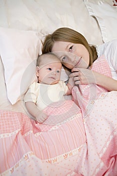 Mother with her baby girl lying on bed