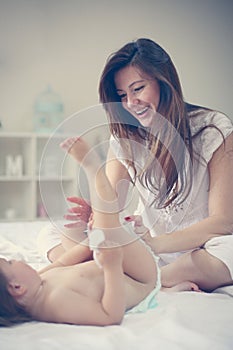 Mother with her baby at home. Mother changing diaper her little