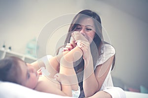 Mother with her baby at home. Mother changing diaper her little