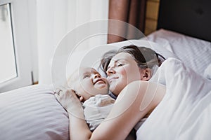 Mother and her baby playing in bed. Happy family concept.