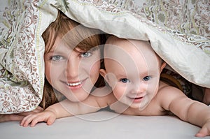 Mother and her baby playing and smiling under a blanket
