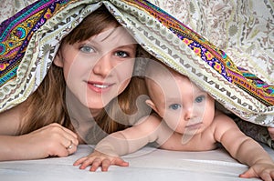 Mother and her baby playing and smiling under a blanket