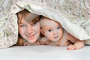 Mother and her baby playing and smiling under a blanket