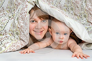 Mother and her baby playing and smiling under a blanket