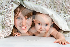 Mother and her baby playing and smiling under a blanket