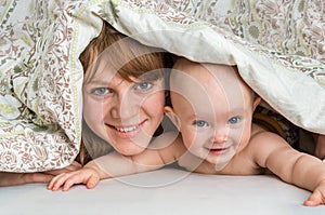 Mother and her baby playing and smiling under a blanket