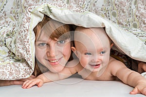 Mother and her baby playing and smiling under a blanket