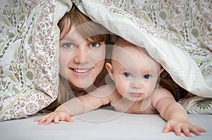 Mother and her baby playing and smiling under a blanket