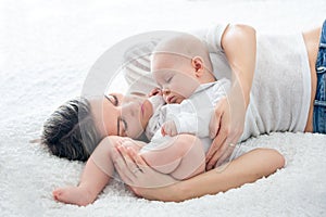 Mother and her baby son, sleeping on a big bed, soft back light