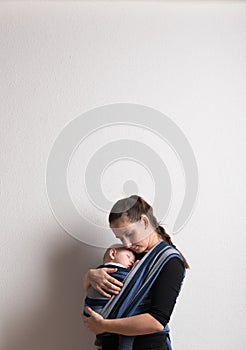 Mother with her baby son sleeping in sling. Studio shot.