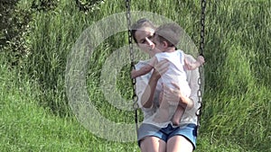 Mother and her baby swing together in the playground