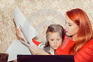 Mother with her child calculating home expenses. Busy Mother With child Running Business From Home looking at bank statement