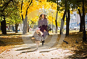 Mother and her child girl playing together on autumn walk in nature outdoors.