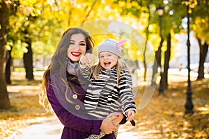 Mother and her child girl playing together on autumn walk in nature outdoors.