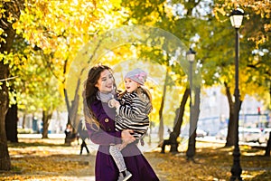 Mother and her child girl playing together on autumn walk in nature outdoors.