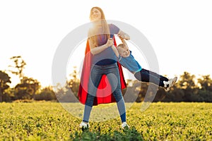 Mother and her child play together . Mom and son in superhero costumes. Mom and baby have fun, smile and hug