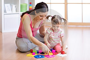 Mother and her child playing with colorful logical sorter toy