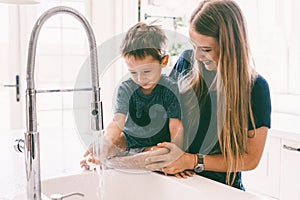 Mother with her child playing in kitchen sink
