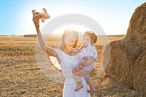 Mother and her child playing with toy airplane in spring field over soft sunlight