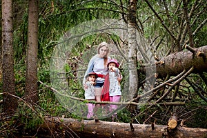Mother and her child sister girls playing and having fun together on walk in forest outdoors. Happy loving family posing on nature