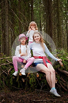 Mother and her child sister girls playing and having fun together on walk in forest outdoors. Happy loving family posing on nature