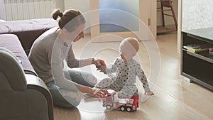 Mother and her child son plays with steering wheel in their living room.