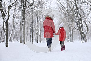 Mother with her child spending time outside on winter day, back view. Christmas vacation