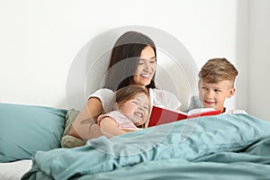 Mother and her children reading book together at home